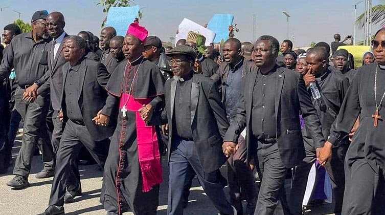 Eine Gruppe von Männern in schwarz gekleidet geht hand in Hand auf einer Straße