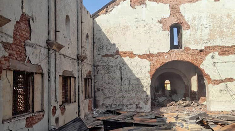 Ein zerstörtes Kirchengebäude im Sudan ohne Dach. Auf dem Boden liegen Trümmerteile. Die Sonne scheint in auf die Überreste der Kirche.