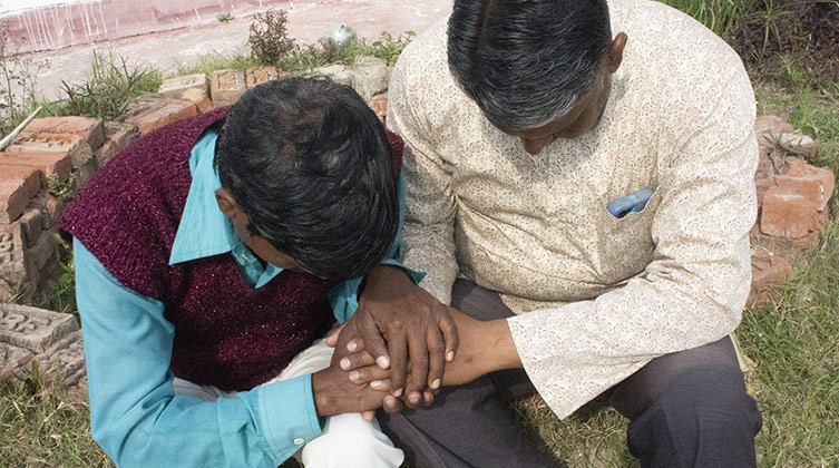 Zwei sitzende indisch aussehende Männer haben die Köpfe geneigt und beten zusammen