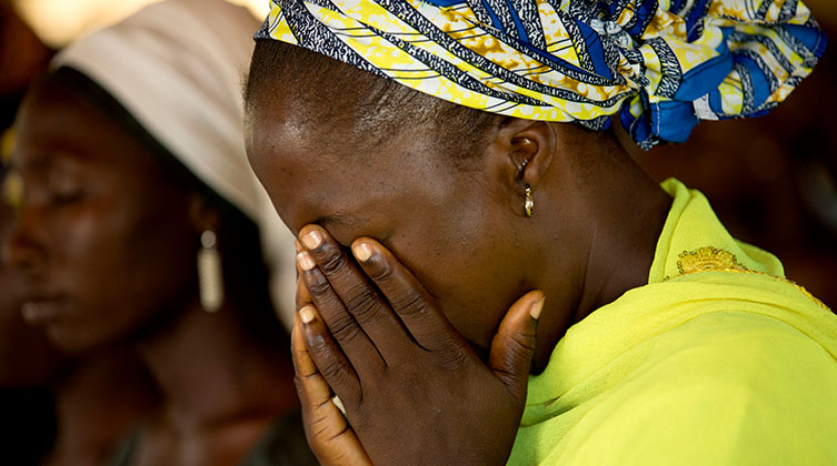 Nigerianische Frau hat ihr Gesicht in ihren Händen vergraben