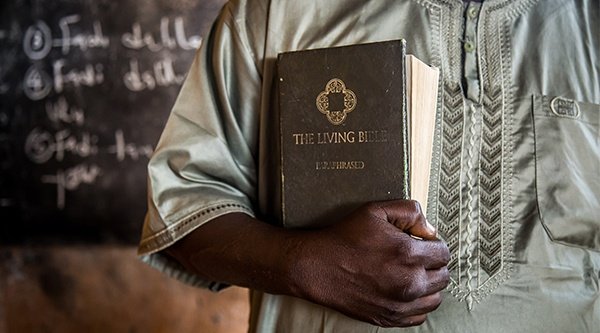 Afrikanischer Mann hält Bibel vor seiner Brust 