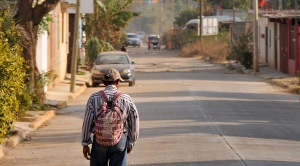 Ein älterer Mann von hinten steht auf einer freien offenen Straße