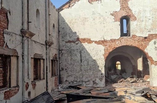 Ein zerstörtes Kirchengebäude im Sudan ohne Dach. Auf dem Boden liegen Trümmerteile. Die Sonne scheint in auf die Überreste der Kirche.