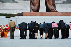 Eine Gruppe von Menschen, die sich vor der gigantischen Bronzestatue des ehemaligen Anführers Kim Il-Sung verbeugen