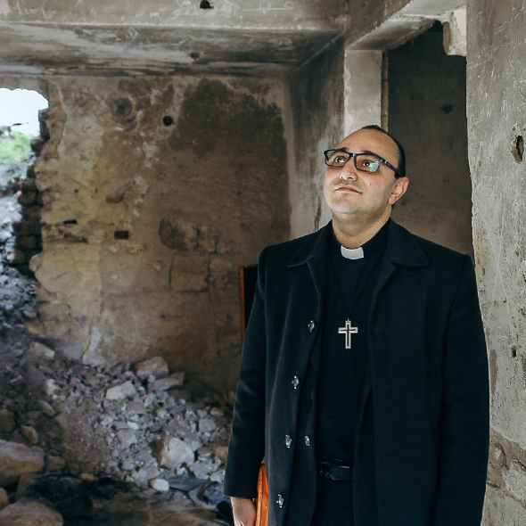 Pastor Abdallah aus Aleppo steht in einem zerstörten Haus