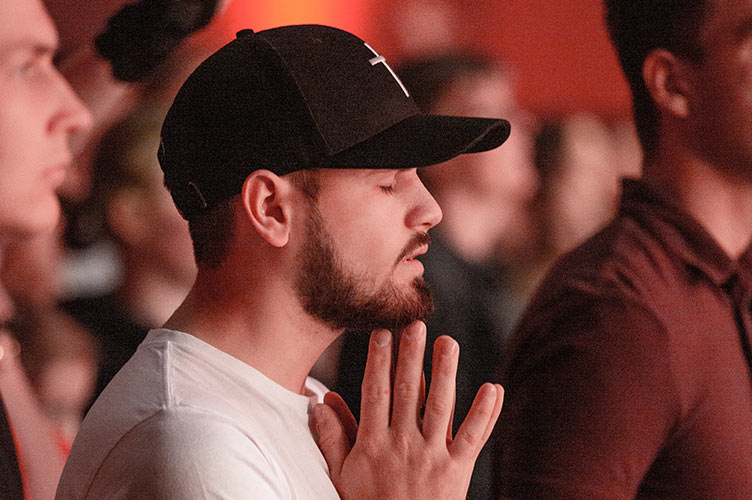 Ein junger Mann mit Kappe betet