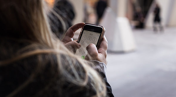 Frau tippt Nummer in ihr Smartphone