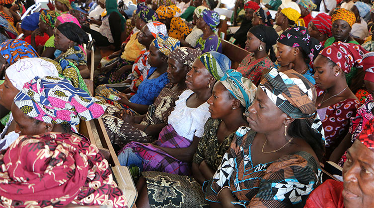 Afrikanische Frauen mit bunter Kleidung sitzen nebeneinander 