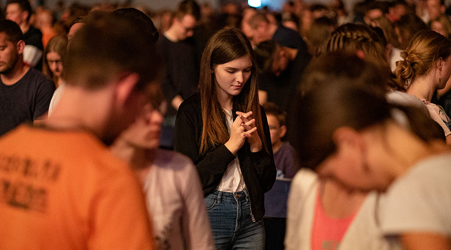 Frau mit gefalteten Händen bei einer Gebetsveranstaltung