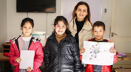 Eine syrische Mutter steht zusammen mit ihren drei Kindern in einem Hoffnungszentrum