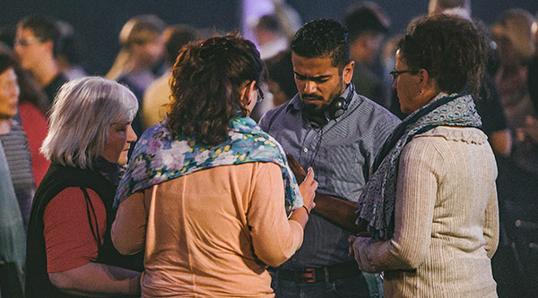 Gruppe von Menschen steht im Kreis und betet 