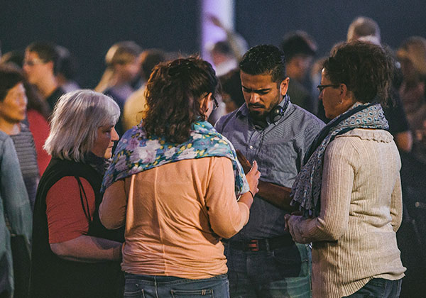 Menschen stehen in kleinen Gruppen im Gebet für verfolgte Christen zusammen