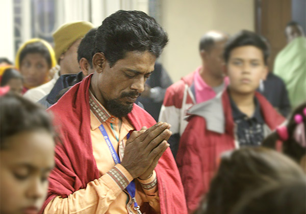 Ein Mann betet mit geschlossenen Augen und gefalteten Händen