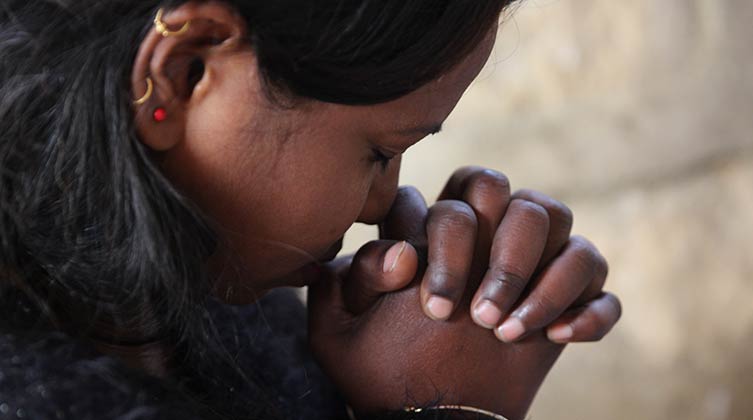 Indische Frau betet mit gefalteten Händen 