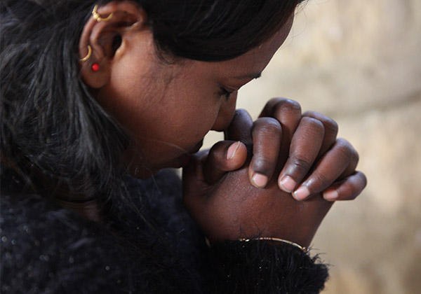 Indische Frau betet mit gefalteten Händen 