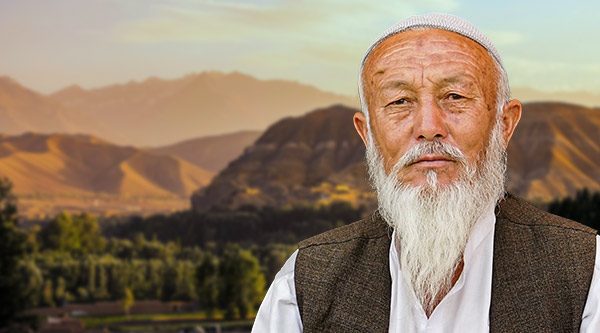 Afghanischer Mann mit weißem Bart und einem ernsten Gesichtsausdruck. Im Hintergrund Berge.