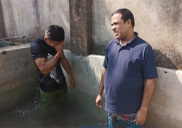 Zwei Männer stehen in einem Taufbecken aus Beton