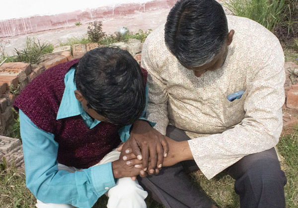 Zwei Männer sitzen zusammen und beten