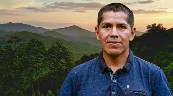 Ein Mann aus Kolumbien steht vor einer Landschaft aus Bergen und Wäldern