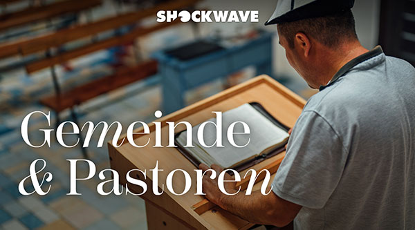 Gemeinde und Pastoren: Ein Mann steht mit einem aufgeschlagenen Buch hinter einer Kanzel
