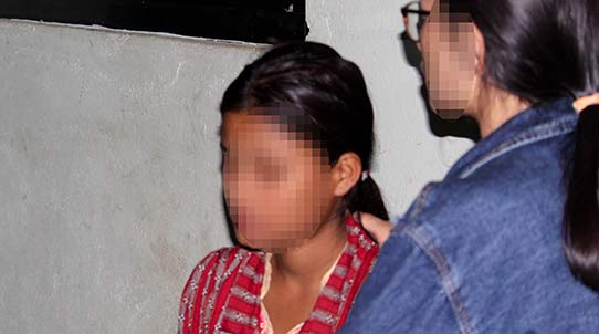 Eine stehende Frau legt einer sitzenden Frau tröstend die Hand auf den Rücken