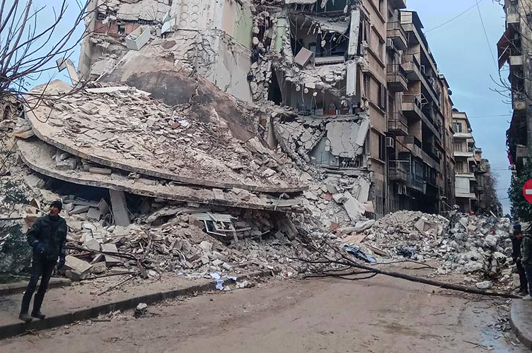 Person steht vor einem vom Erdbeben zerstörten Haus in Aleppo