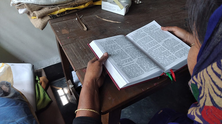 Eine Frau mit einem Tuch über dem Kopf ließt eine Bibel