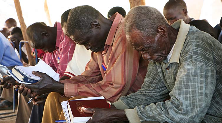 Männer mit Bibeln in den Händen am beten