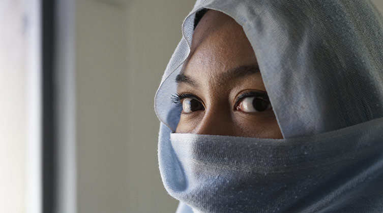 Eine Frau verhüllt ihr Gesicht mit einem blauen Schleier