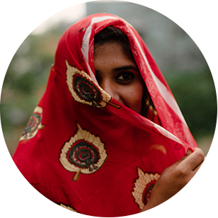 Gesicht einer zur rechten Gesichtshälfte verschleierten indischen Frau mit rotem Sari