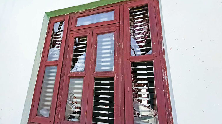Ein rotes Fenster mit eingeschlagenen Scheiben.