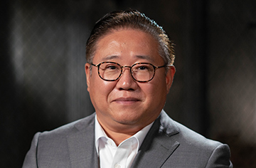 Asiatischer Mann mit Brille blickt in die Kamera