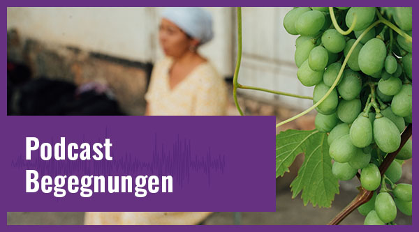 Eine Frau sitzt betend auf einer Stufe im Vordergrund eine Weinrebe