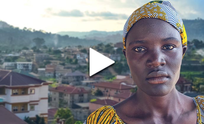 Eine Dame aus Kamerun mit verschlossenem Blick ist vor dem Hintergrund einer Stadtszene