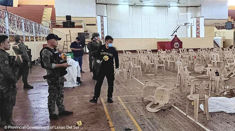 Einsatzkräfte stehen zwischen Trümmern in einer Turnhalle