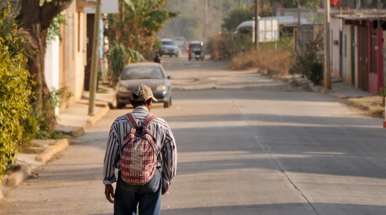 Ein älterer Mann von hinten steht auf einer freien offenen Straße