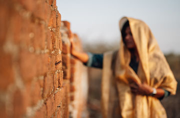 Eine indische Christen stützt sich an eine Mauer