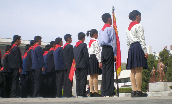 Kinder in Uniform stehen vor Statuen