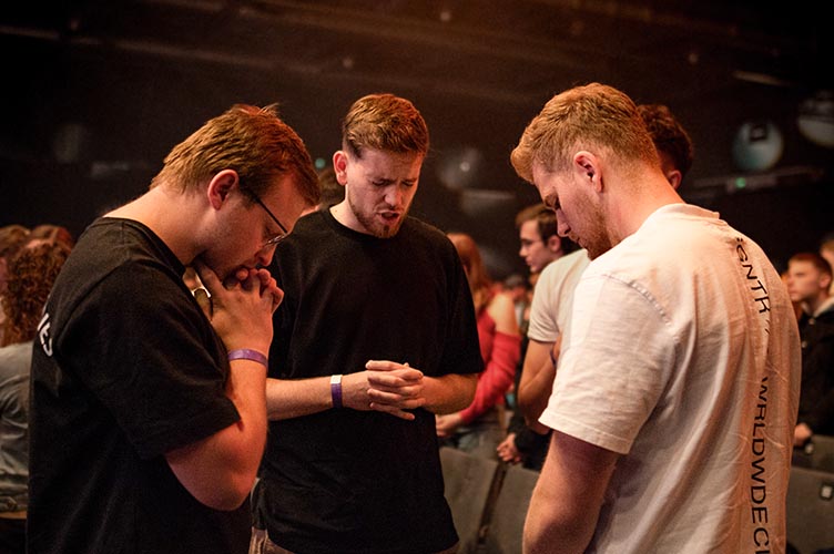 Drei junge Männer beten in einer Kleingruppe