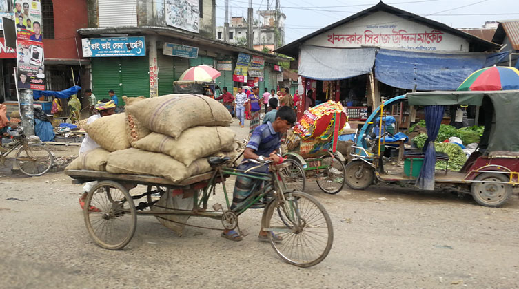 Ein Mann in Bangladesch schiebt sein Lastenfahrrad in der Hauptstadt Dhaka