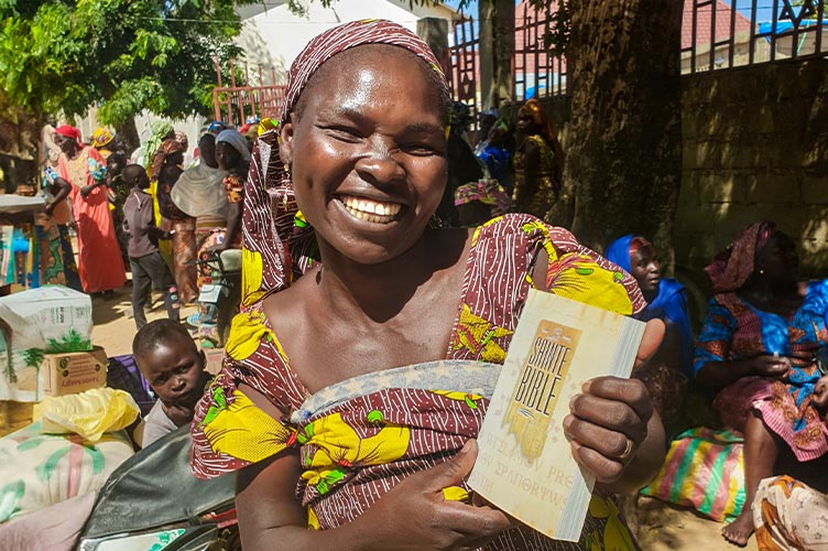 Eine lächelnde Christin hält voller Freude eine Bibel in ihrer Hand.