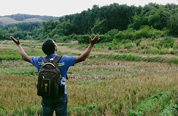 Ein Mann steht auf einer Wiese und hebt seine Hände