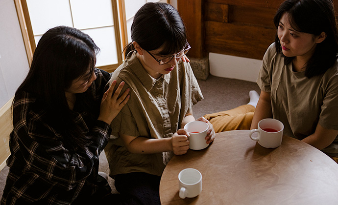 Nachgestellte Szene: Drei nordkoreanische Frauen sitzen an einem Tisch mit Tassen in der Hand