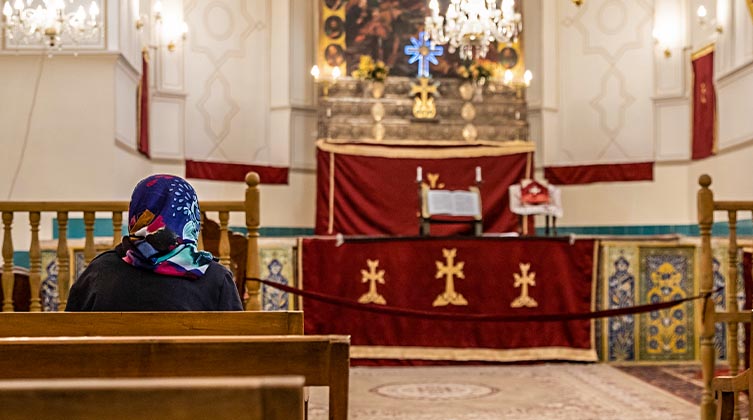 Eine Frau mit einer Kopfbedeckung sitzt in einer Kirche