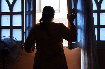 Frau steht vor einem offenen Fenster