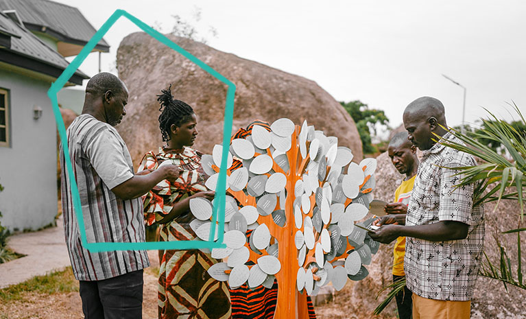 Afrikanische Christen stehen vor dem Baum der Ermutigung.