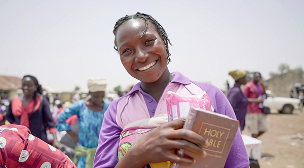 Eine Frau hält lächelnd eine neue Bibel in der Hand