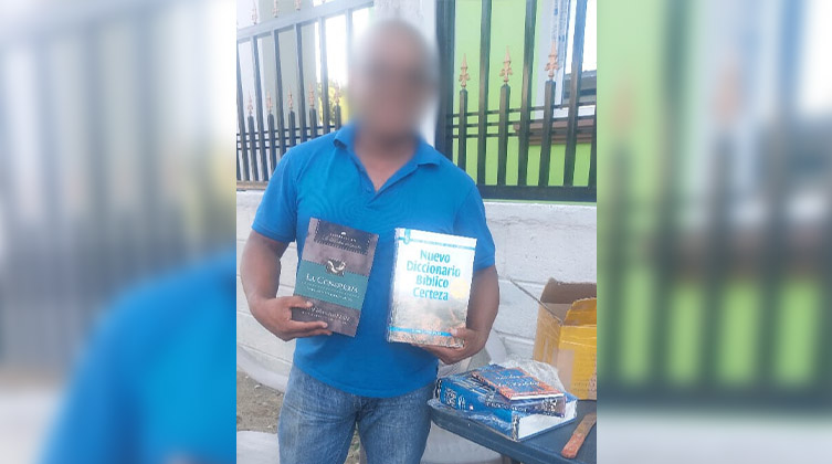 Ein Mann mit blauem Hemd hält Schulungsmaterial in beiden Händen.