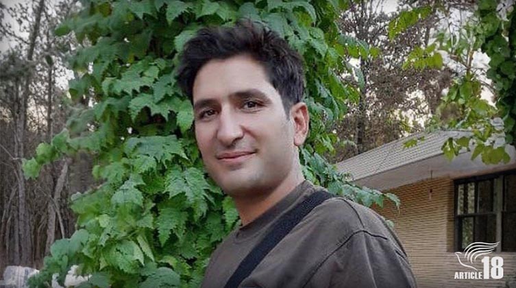 Ein junger Mann steht vor einem Haus im Wald