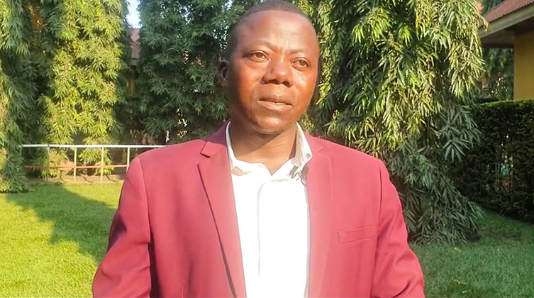 Ein Mann mit Anzug steht vor der Kamera